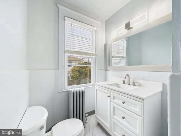 a bathroom with a toilet sink a mirror and a window