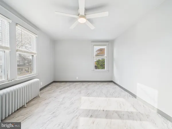 an empty room with windows and ceiling fan