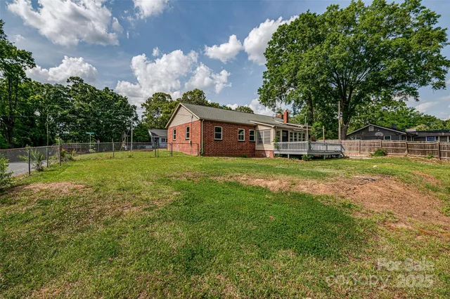 a backyard of a house with plants and large tree