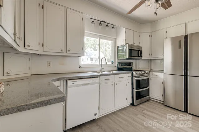 a kitchen with granite countertop white cabinets and white appliances