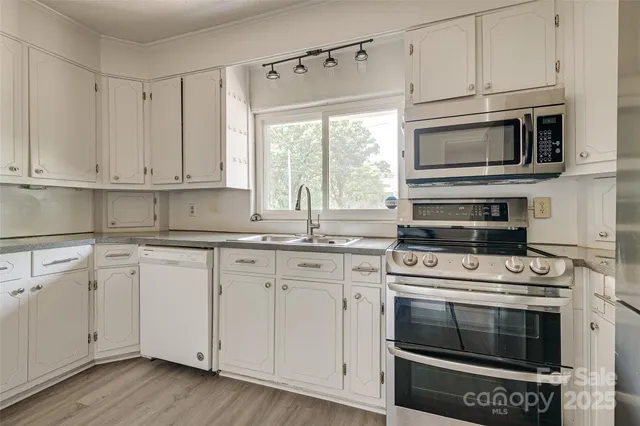 a kitchen with granite countertop white cabinets white stainless steel appliances and a sink