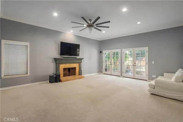 a view of a livingroom with a fireplace a ceiling fan and windows