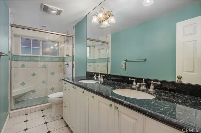 a bathroom with a granite countertop sink a toilet a mirror and shower