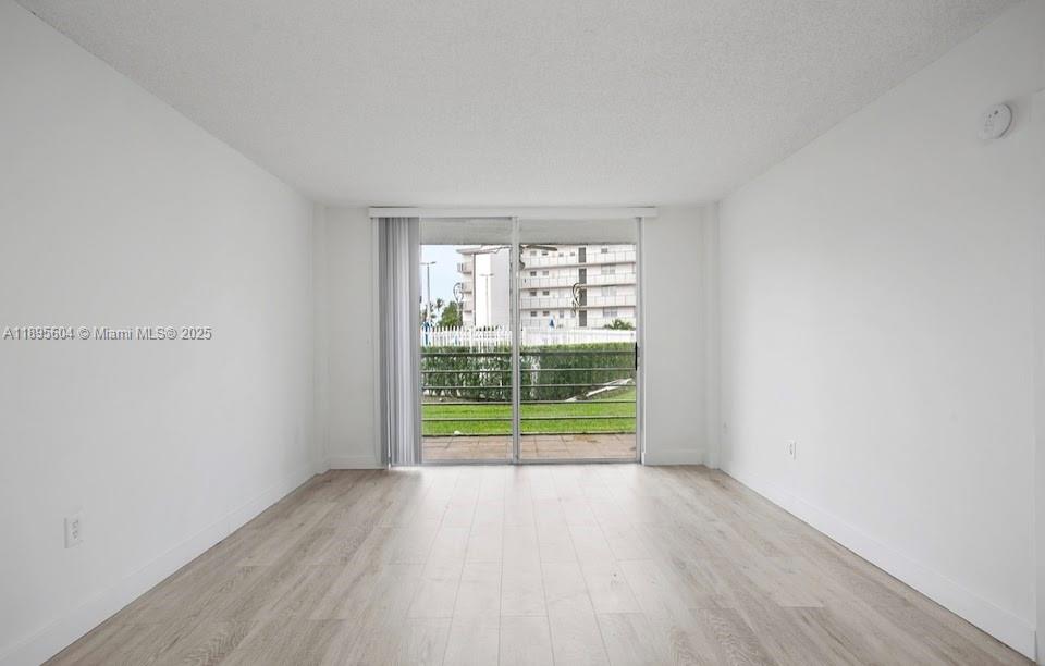 14140 Southwest 84th Street, Unit 104H Miami, FL 33183 - Photo 4 of 13 an empty room with wooden floor and windows