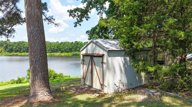 a view of a wooden house with a small yard and large tree