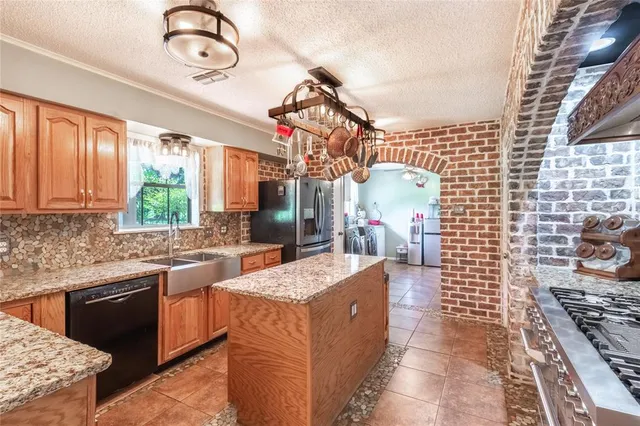 a kitchen with kitchen island granite countertop a stove a sink dishwasher and cabinets with wooden floor