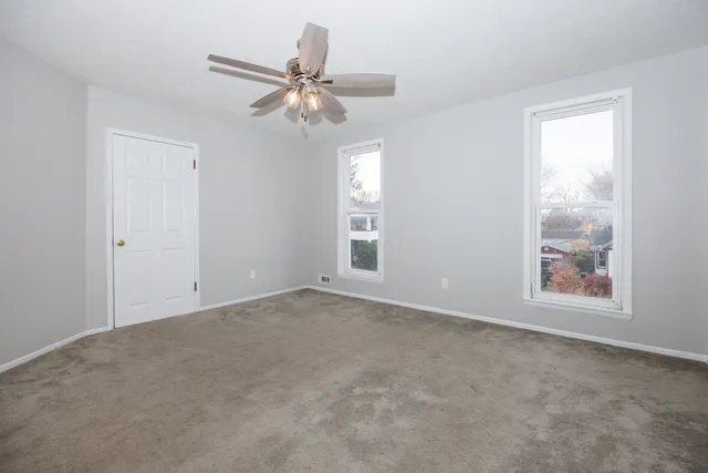 an empty room with windows and fan