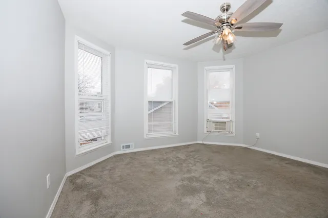 an empty room with windows and fan