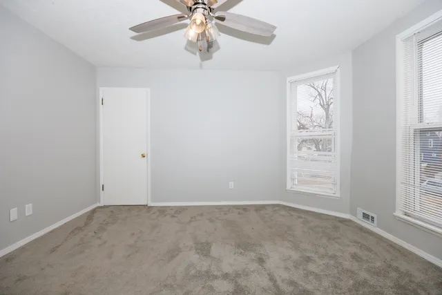 an empty room with windows and fan