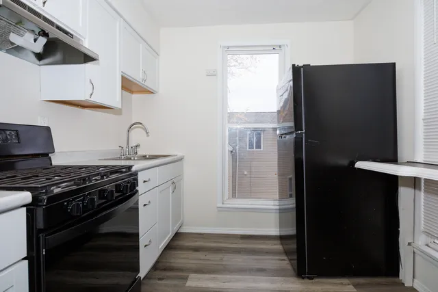 a kitchen with stainless steel appliances a refrigerator a stove and white cabinets