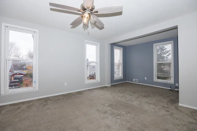 an empty room with windows and fan