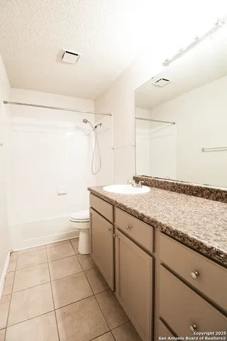 a bathroom with a granite countertop sink a toilet and a bathtub