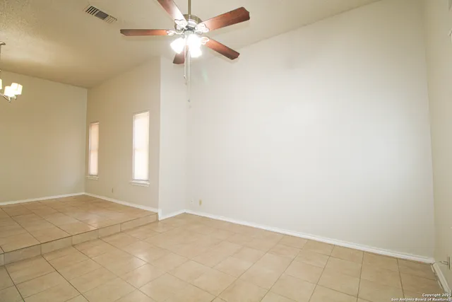 an empty room with windows and fan