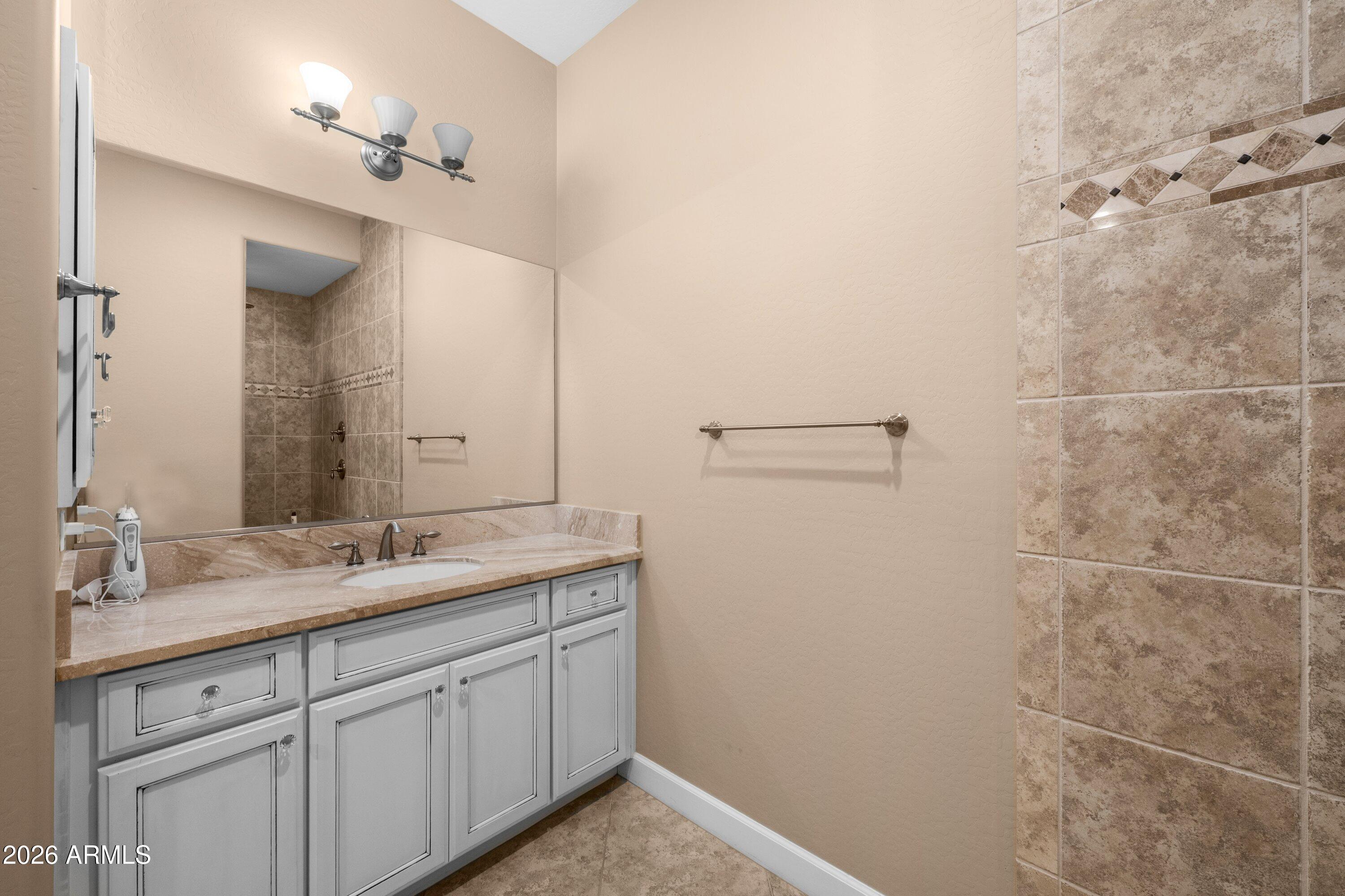 3738 East Riopelle Avenue Gilbert, AZ 85298 - Photo 31 of 97 a bathroom with a granite countertop sink a mirror and a shower