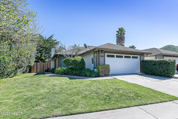 a front view of a house with a yard and potted plants