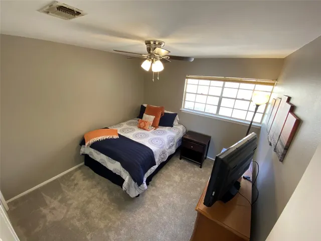 a bedroom with a bed and a flat tv screen on dresser