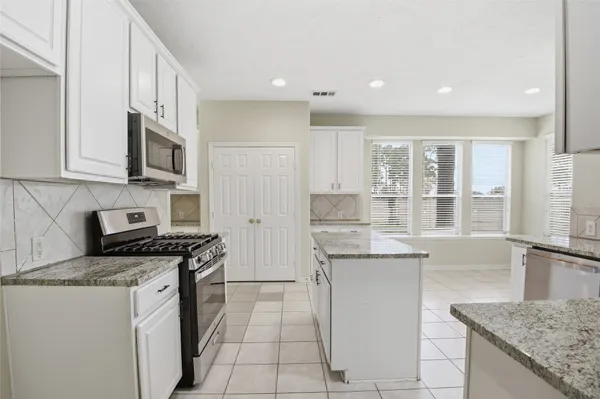 a kitchen with stainless steel appliances granite countertop a stove a sink and a microwave