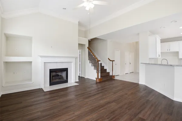 a view of an empty room with wooden floor a fireplace and a window