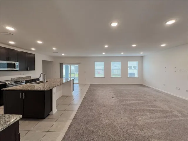 a view of a kitchen with kitchen island a sink wooden floor and black appliances