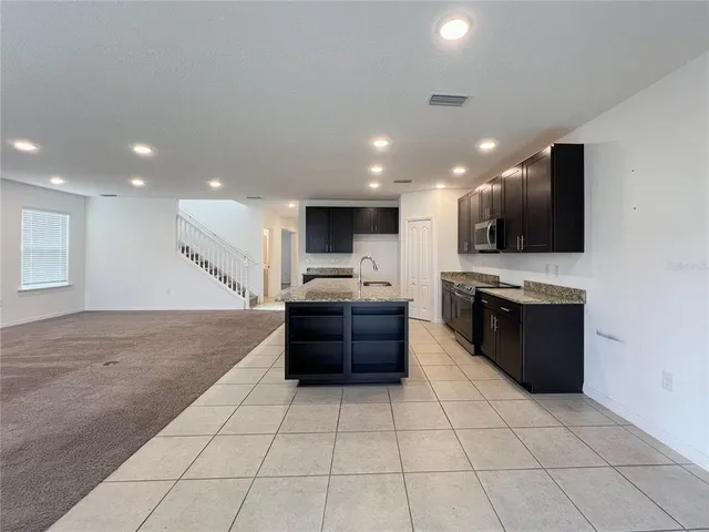 a large kitchen with a large counter top a stove a sink and a refrigerator