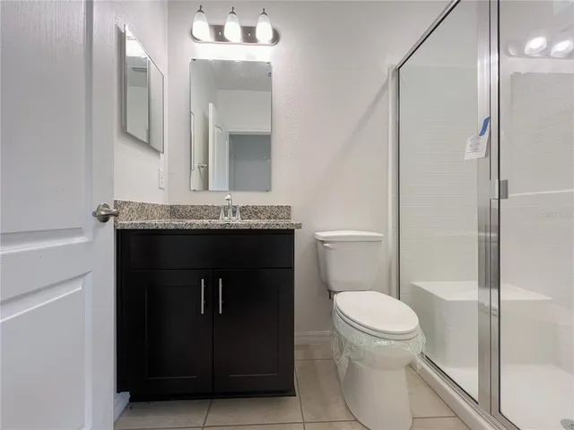 a bathroom with a granite countertop toilet sink and mirror