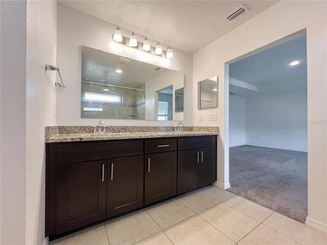 a bathroom with a granite countertop double vanity and a mirror
