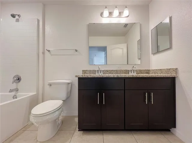a bathroom with a granite countertop sink a toilet and a mirror