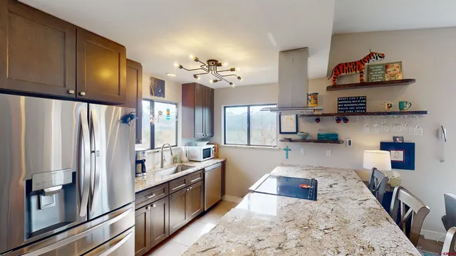 a kitchen with stainless steel appliances granite countertop a refrigerator a stove and a sink with wooden floor