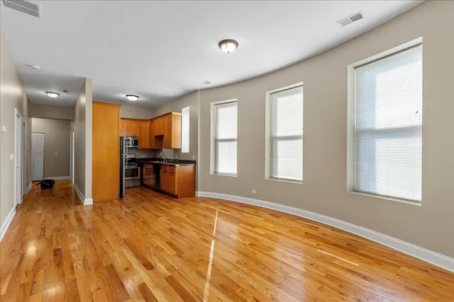 a view of a kitchen with kitchen island wooden floor stainless steel appliances and windows