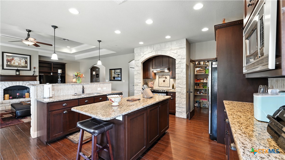 121 Carrizo Ridge Floresville, TX 78114 - Photo 15 of 43 a large kitchen with stainless steel appliances kitchen island granite countertop a large stove a sink dishwasher and cabinets with wooden floor