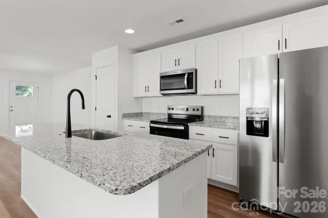 a kitchen with stainless steel appliances granite countertop a sink a stove a refrigerator a microwave and cabinets