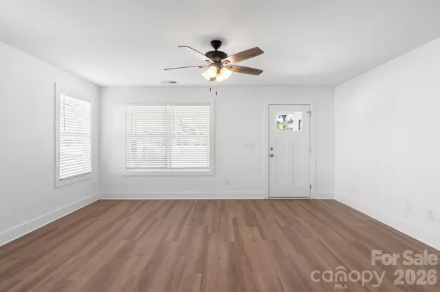 a view of empty room with wooden floor and fan