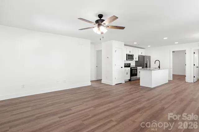 a view of a kitchen with a sink a refrigerator a ceiling fan and wooden floor