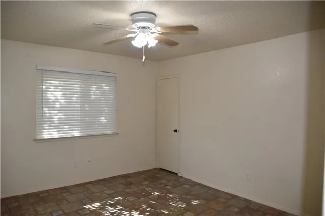 a view of a big room with a window and a chandelier fan