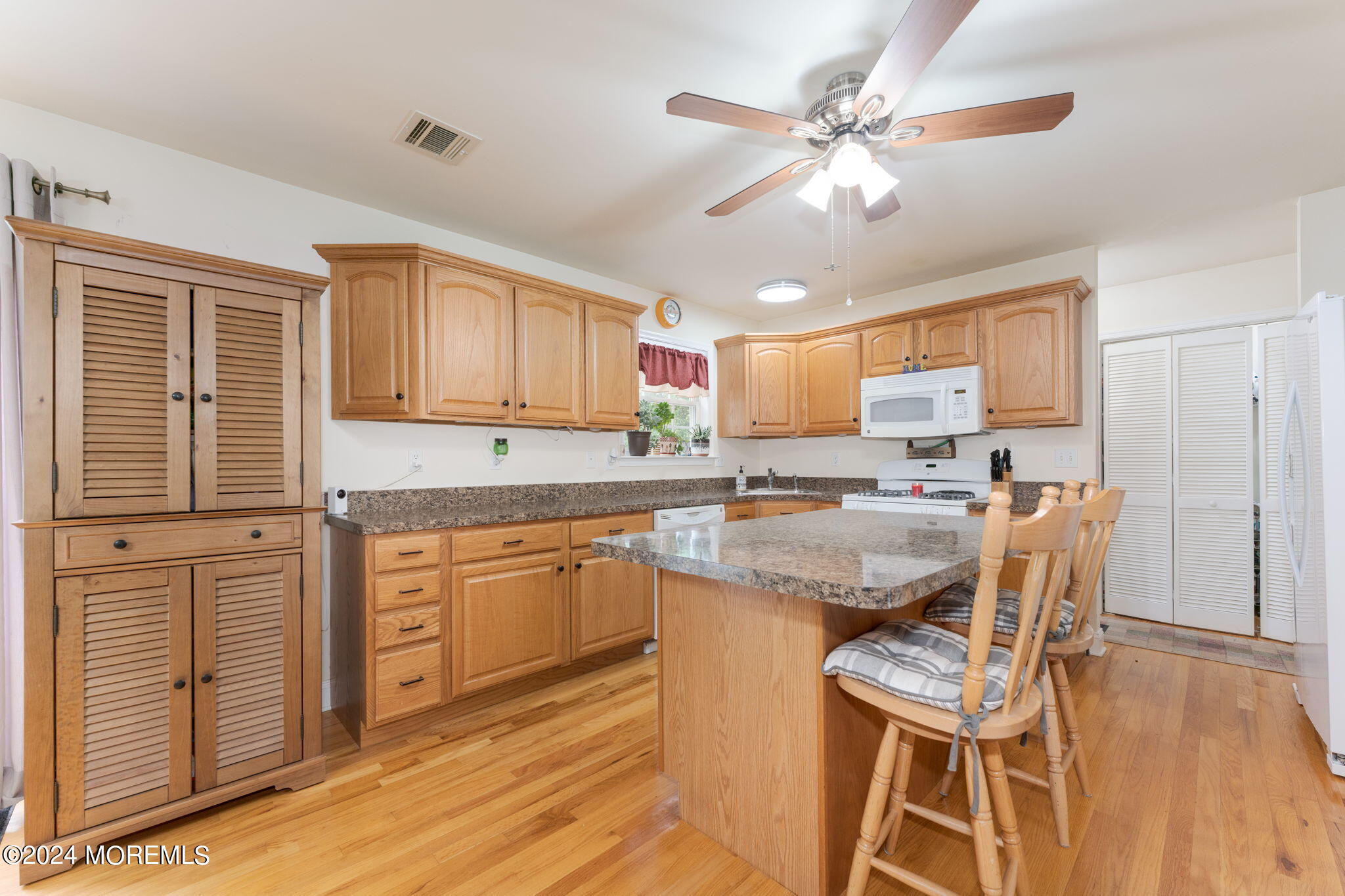 83 Gunning River Road Barnegat, NJ 08005 - Photo 6 of 24 a kitchen with stainless steel appliances granite countertop a stove top oven a sink a dining table and chairs with wooden floor