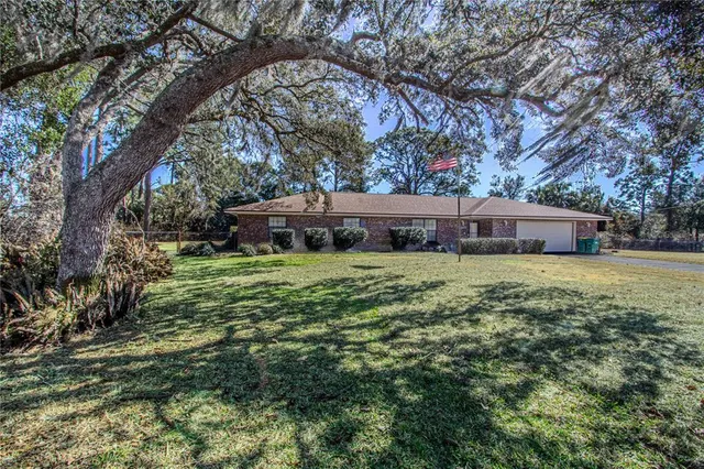 a front view of house with yard and trees in the background