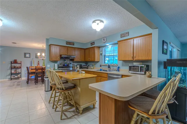 a kitchen with stainless steel appliances granite countertop a sink dishwasher a stove a refrigerator with a dining table and chairs with wooden floor