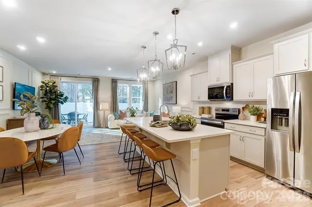 a view of a dining room with furniture a kitchen and chandelier