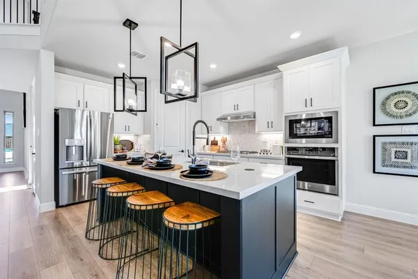 a kitchen with kitchen island granite countertop a sink a stove and a wooden floors