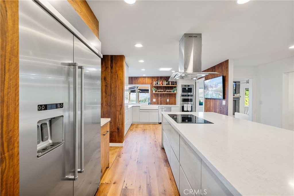 16337 Ravenglen Road Canyon Country, CA 91387 - Photo 9 of 50 a kitchen with stainless steel appliances a refrigerator and a wooden floor
