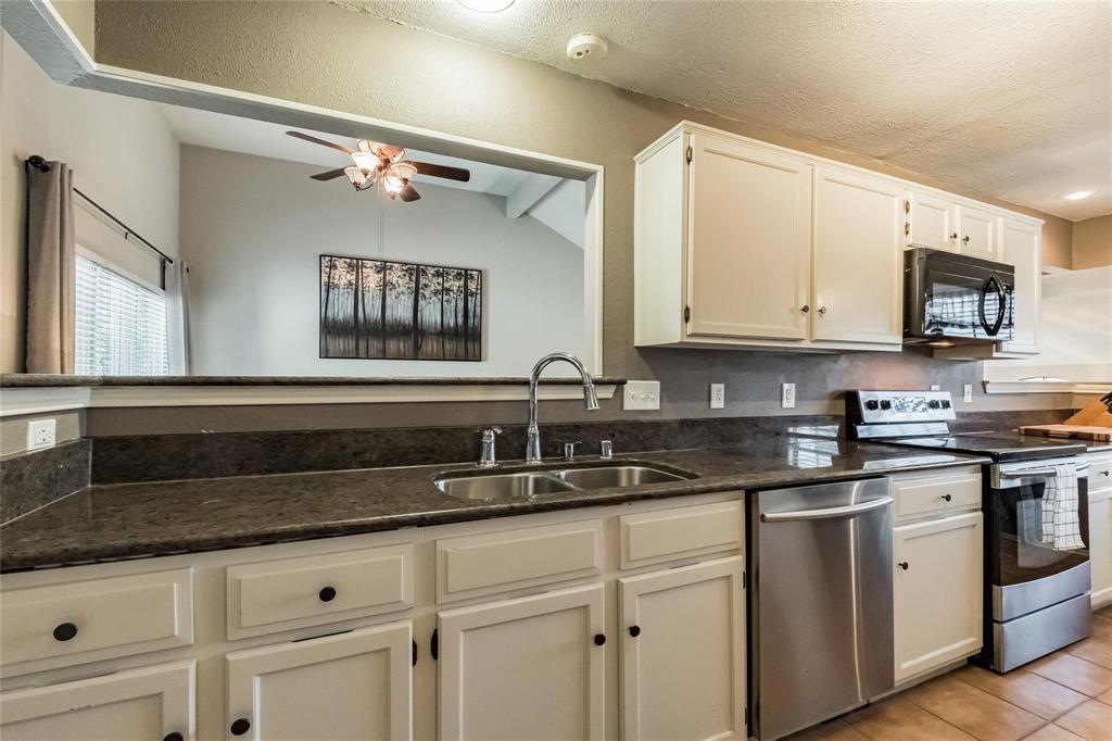 2939 Hunters Point Lane Carrollton, TX 75007 - Photo 21 of 29 a kitchen with granite countertop white cabinets and white appliances