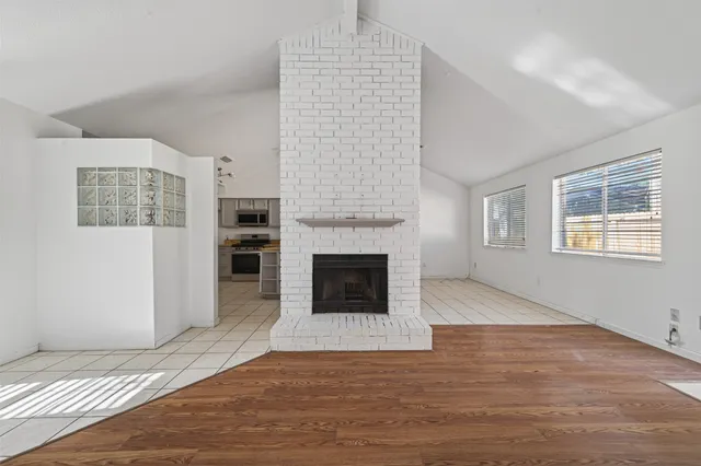 a view of empty room with wooden floor and fireplace