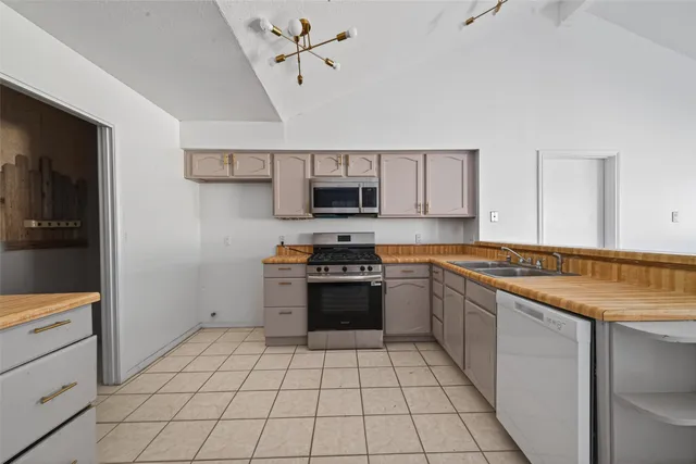 a large kitchen with stainless steel appliances kitchen island granite countertop a refrigerator and a stove top oven