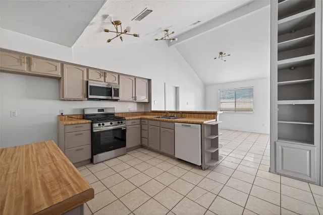 a kitchen with stainless steel appliances granite countertop a stove top oven a sink dishwasher and a refrigerator