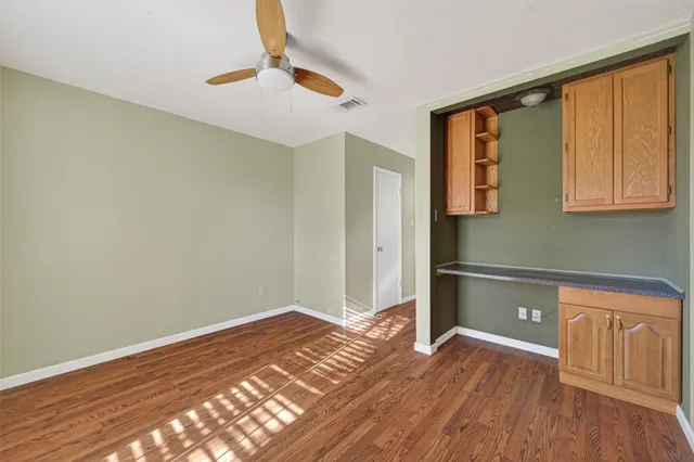a view of a room with wooden floor and a ceiling fan