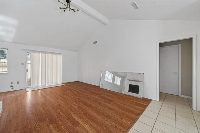 a view of an empty room with wooden floor and a fireplace