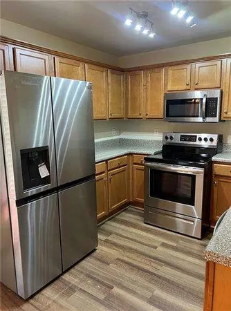 a kitchen with stainless steel appliances granite countertop a refrigerator a stove a sink and a microwave
