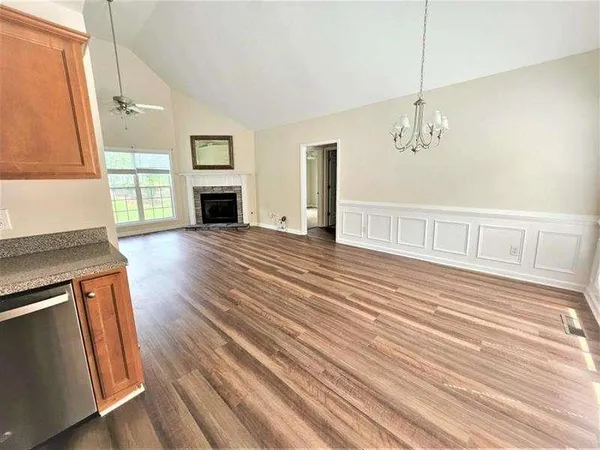 an empty room with wooden floor fireplace and windows