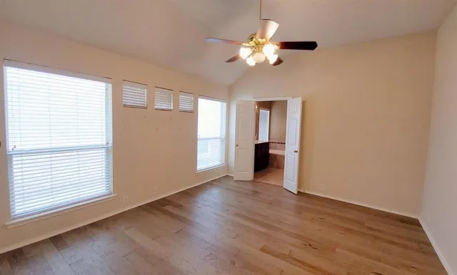 a view of an empty room with a window and wooden floor