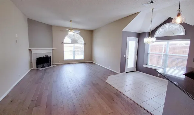 an empty room with wooden floor fireplace and windows